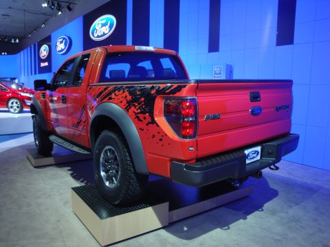 1993 Ford Taurus - A red Ford F-150 Raptor pickup truck is displayed at an auto show with Ford branding in the background.