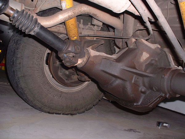 Rear axle assembly and driveshaft of a vehicle, showing a U-joint and part of a tire