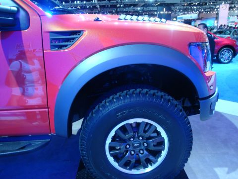 1993 Ford Taurus - A close-up view of the fender and wheel of a red truck, possibly at an auto show.