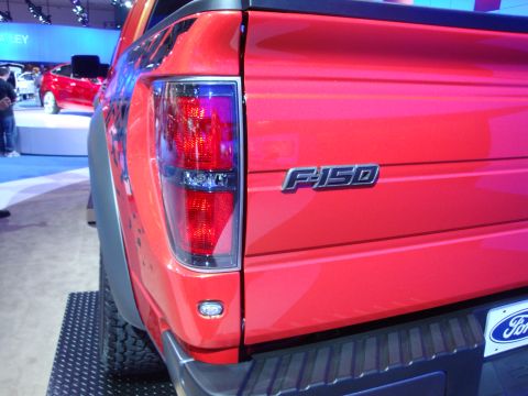 1993 Ford Taurus - Rear view of a red Ford F-150 pickup truck at an auto show. Another vehicle is in the background.