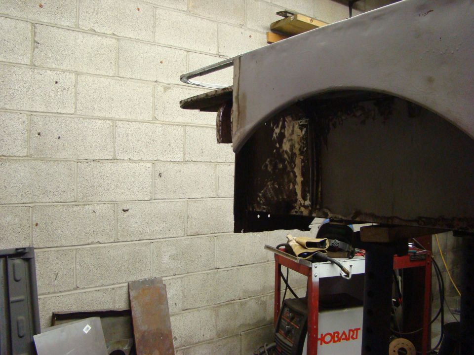 Rusted wheel well and fender section, likely from a vintage vehicle undergoing repair