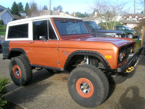 1972 Ford Bronco - This 1972 Ford Bronco features a distinctive orange paint job, a white hardtop, and aggressive off-road tires.