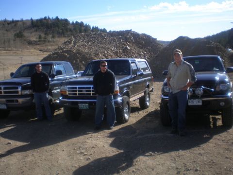1996 Ford Bronco - Three men pose with their vehicles in an outdoor, rocky area under a clear blue sky.