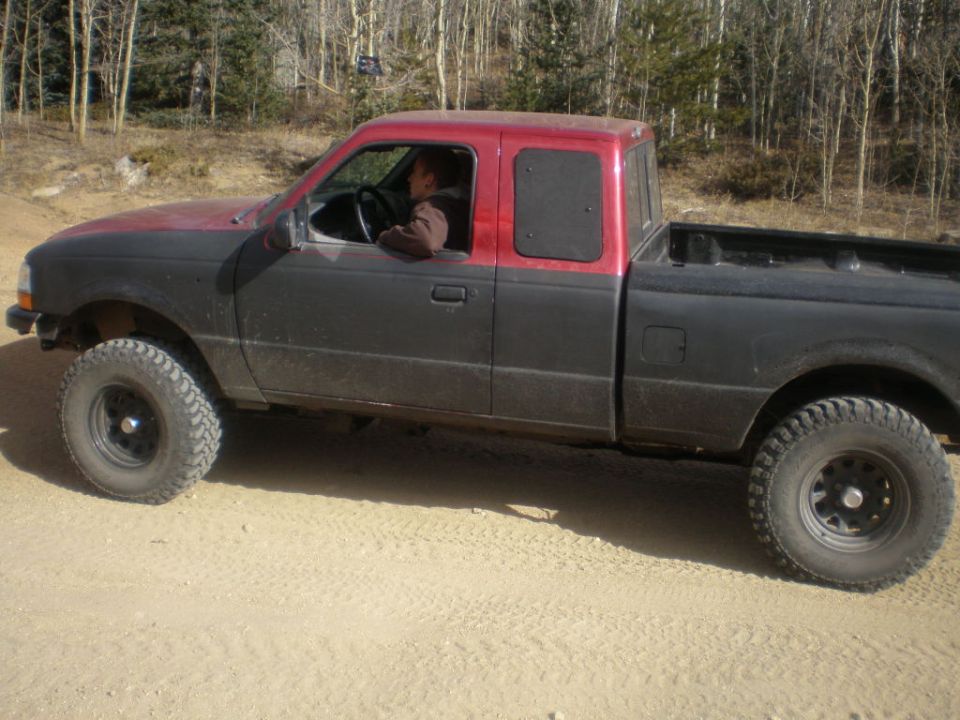 Two-tone red and black Ford Ranger pickup truck with lifted suspension and off-road tires