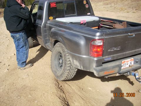 2004 Ford Ranger - A 2004 Ford Ranger pickup truck is seen from the rear, parked on a dirt path with a person standing by the driver's door.