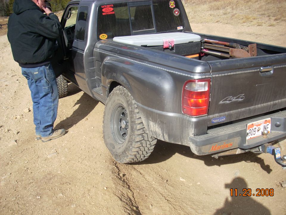 Dark gray 2004 Ford Ranger pickup truck with a toolbox in the bed, parked on a dirt road