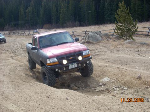 2004 Ford Ranger - This pickup truck is navigating a rough, off-road terrain with trees and a wooden fence in the background.