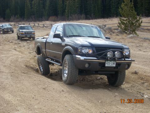 2004 Ford Ranger - A dark gray 2004 Ford Ranger navigates a dirt path with other vehicles in the background.