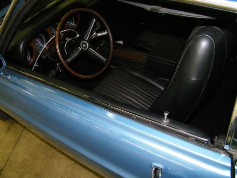 1968 Ford Mustang - Interior view of a classic car, black vinyl seats and a wood-accented dashboard.