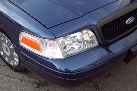 2001 Ford Crown Victoria - Close-up of the front of a blue Ford Crown Victoria, highlighting its grille and headlight assembly.