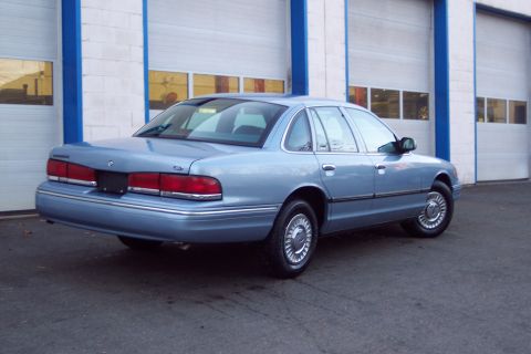 2001 Ford Crown Victoria - This 2001 Ford Crown Victoria is shown from the rear three-quarter angle, parked in front of a building with garage doors.