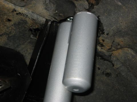 1995 Ford Bronco - Two silver shock absorbers are visible, mounted to the rusty undercarriage of a vehicle.