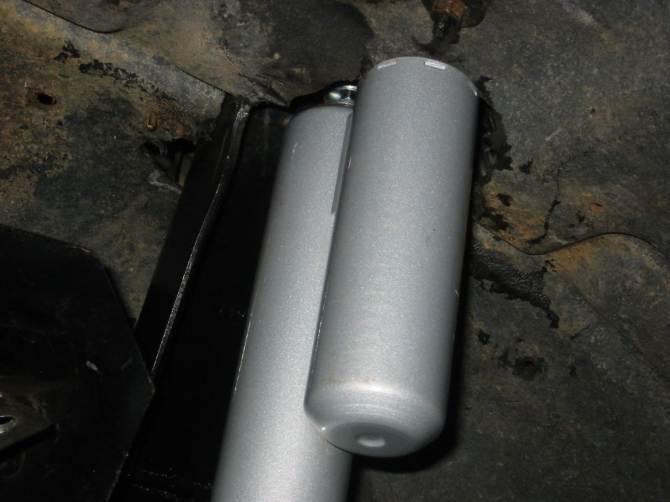 close-up of two silver shock absorbers mounted on a vehicle's undercarriage