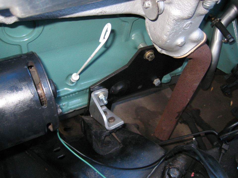 Close-up of engine bay showing a dipstick, exhaust pipe, and mounting bracket