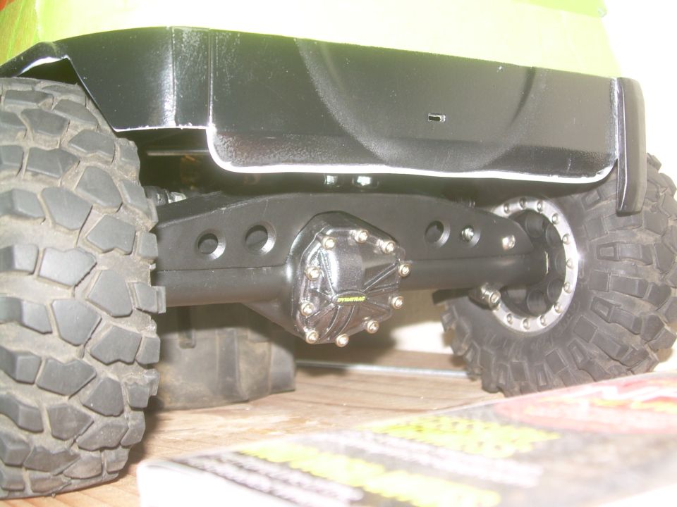 Close-up of a heavy-duty rear axle with a differential cover and a large, knobby tire
