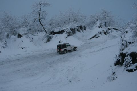 1990 Chevrolet Suburban - A white Jeep Wrangler navigates a snowy landscape with snow-covered trees and terrain.