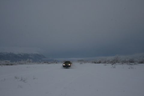 1990 Chevrolet Suburban - A yellow SUV navigates a snow-covered landscape under a cloudy sky.