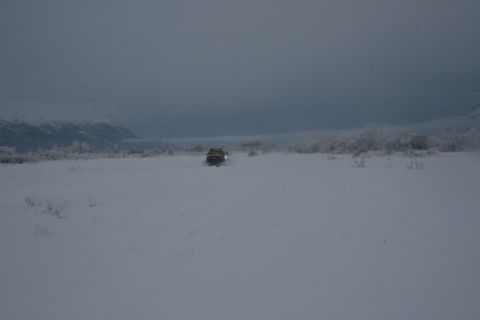 1990 Chevrolet Suburban - Vehicle navigates a wide, snow-covered plain with trees and mountains in the background.