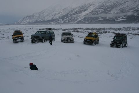 1990 Chevrolet Suburban - A group of SUVs and Jeeps are parked in a snowy, remote landscape, suggesting an expedition or off-road adventure.
