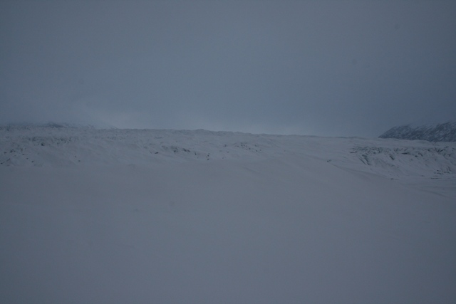 Vast snowy landscape with a cloudy sky and distant mountains