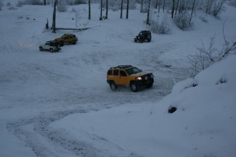 1990 Chevrolet Suburban - Multiple SUVs navigate a snow-covered landscape, suggesting off-road or winter conditions.