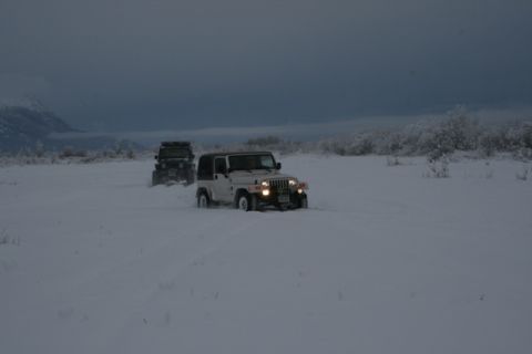 1990 Chevrolet Suburban - Two Jeeps navigate a snowy landscape under a cloudy sky.
