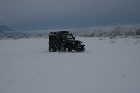 1990 Chevrolet Suburban - Jeep Wrangler navigating a snowy landscape under a cloudy sky.