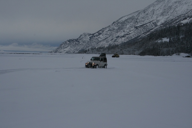 White Jeep Wrangler driving through snow with other vehicles in distance