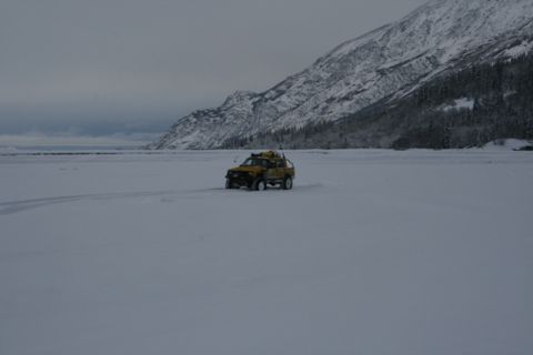 1990 Chevrolet Suburban - A yellow pickup truck traverses a vast, snow-covered landscape under a cloudy sky.