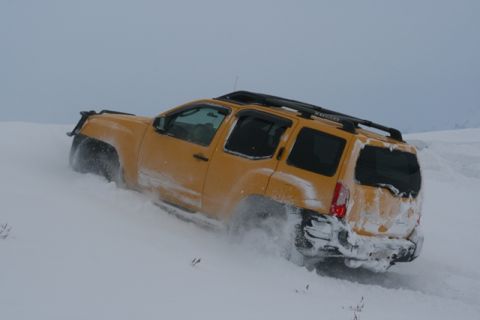 1990 Chevrolet Suburban - A yellow SUV navigates a snow-covered landscape, its tires churning through the deep snow.