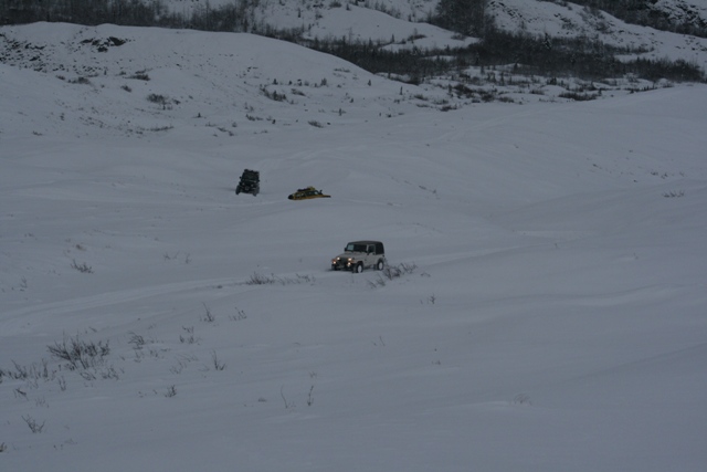 White Jeep Wrangler driving on a snowy landscape