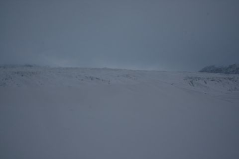 1990 Chevrolet Suburban - A wide, snow-covered landscape stretches towards a hazy mountain range under an overcast sky.