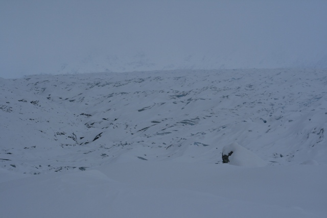 Snow-covered ground with textured ice formations under a hazy sky
