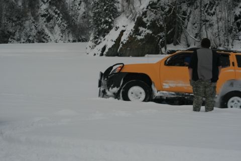 1990 Chevrolet Suburban - An orange SUV is stuck in deep snow, with a person standing next to it in a snowy landscape.