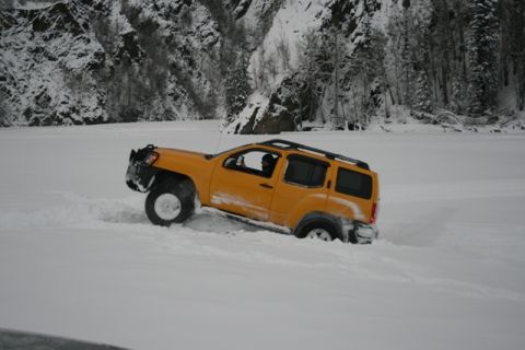 1990 Chevrolet Suburban - SUV stuck in snowdrift with snowy mountains and trees in background.
