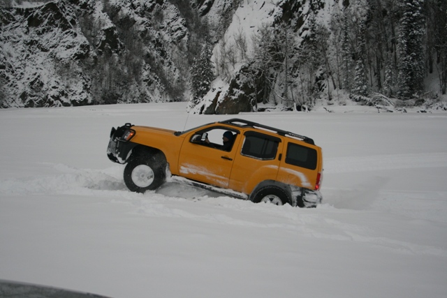 Yellow SUV with roof rack stuck in deep snow, front wheel turned