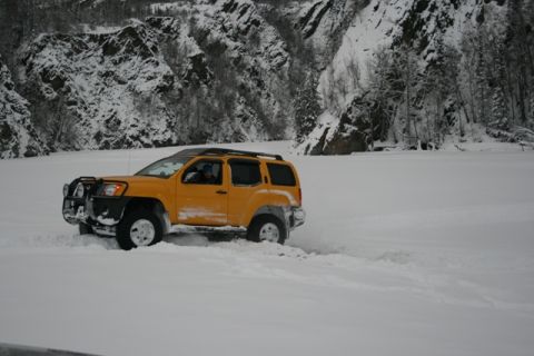 1990 Chevrolet Suburban - SUV navigating a snow-covered landscape near a mountain.