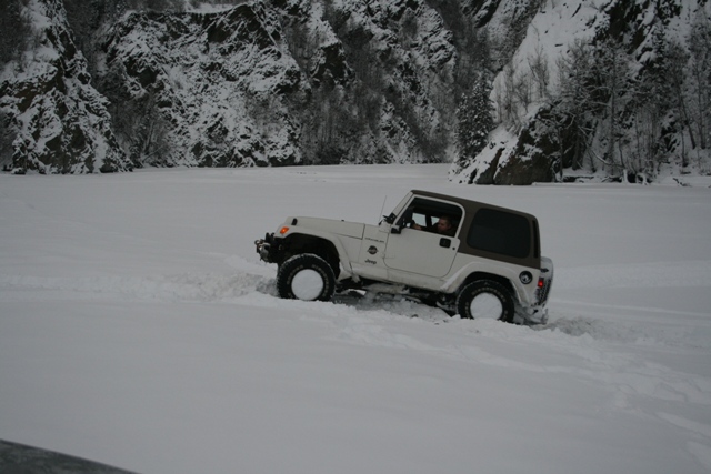 White Jeep Wrangler driving through deep snow with brown top