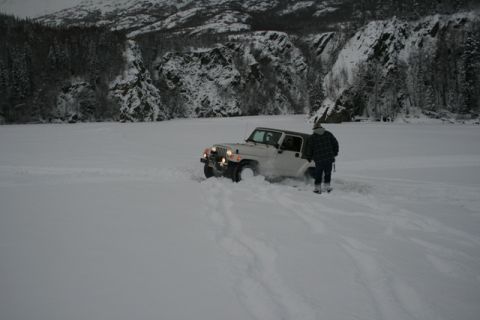 1990 Chevrolet Suburban - Jeep Wrangler stuck in deep snow with a person observing the situation.