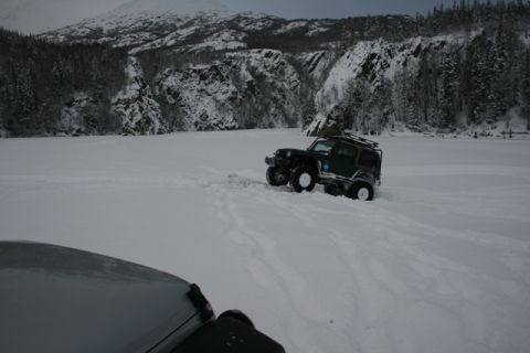 1990 Chevrolet Suburban - A Jeep Wrangler navigates a snow-covered landscape with mountains in the background.