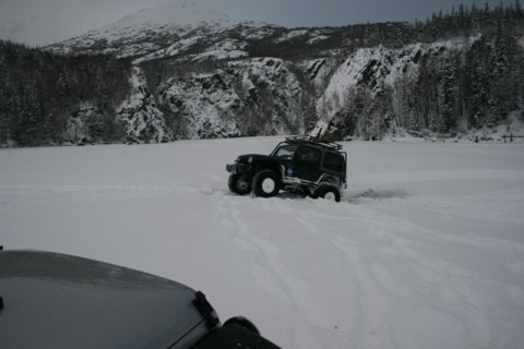 1990 Chevrolet Suburban - A Jeep Wrangler navigates a snow-covered landscape, with a second vehicle in the foreground.