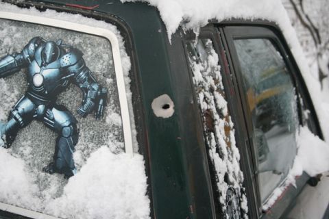1990 Chevrolet Suburban - A rear window features an Iron Man sticker and a bullet hole, with snow covering the vehicle.