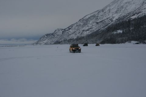 1990 Chevrolet Suburban - Several vehicles traverse a vast, snow-covered landscape under a cloudy sky.