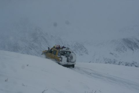 1990 Chevrolet Suburban - SUV navigating a snow-covered mountain road with heavy snowfall.