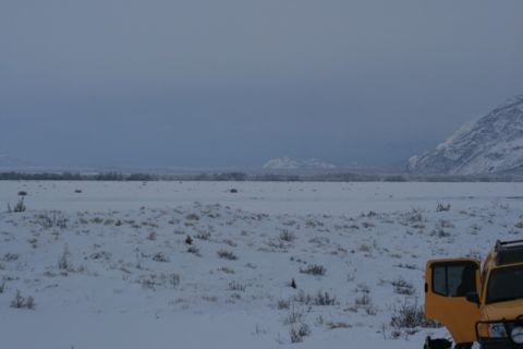 1990 Chevrolet Suburban - A yellow SUV is parked in a vast, snow-covered landscape under a cloudy sky.
