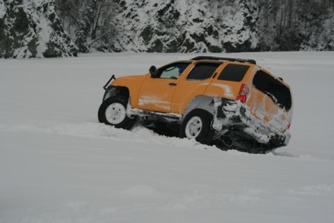 1990 Chevrolet Suburban - SUV stuck in snowdrift with visible damage to the rear.