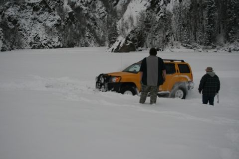 1990 Chevrolet Suburban - A yellow SUV is stuck in a snowy landscape with two individuals observing the situation.