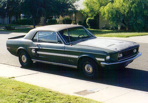 Dark green 1969 Mustang coupe parked on street, side view