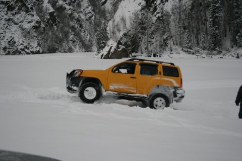 1990 Chevrolet Suburban - A yellow SUV navigates a snowy landscape, its front bull bar visible as it drives through deep snow.