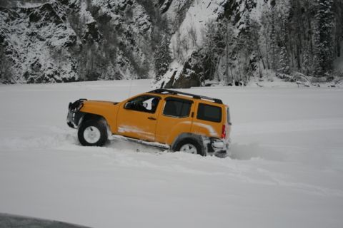 1990 Chevrolet Suburban - A yellow SUV navigates a snow-covered landscape with a mountainous backdrop.